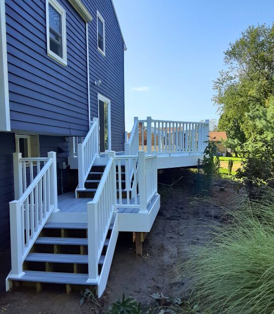 multi-tiered vinyl deck attached to a blue single family home.